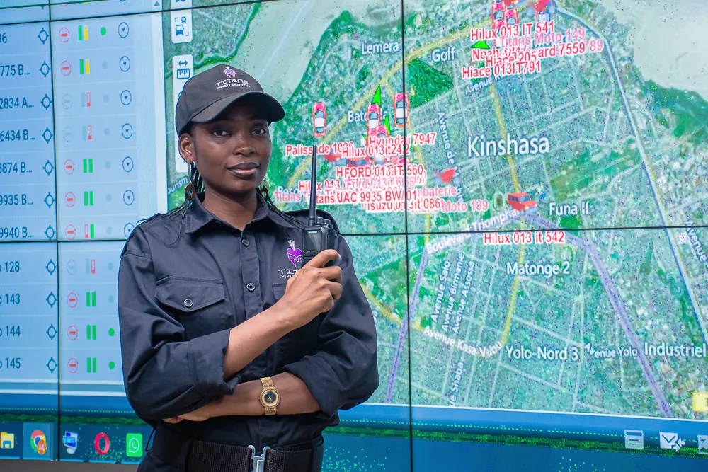 Titans security officer holding a radio in front of monitoring screens