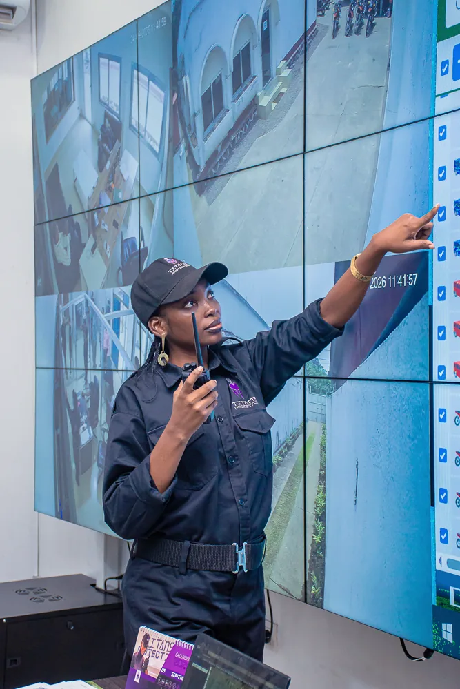 Titans officer pointing to CCTV screens while holding a handheld radio