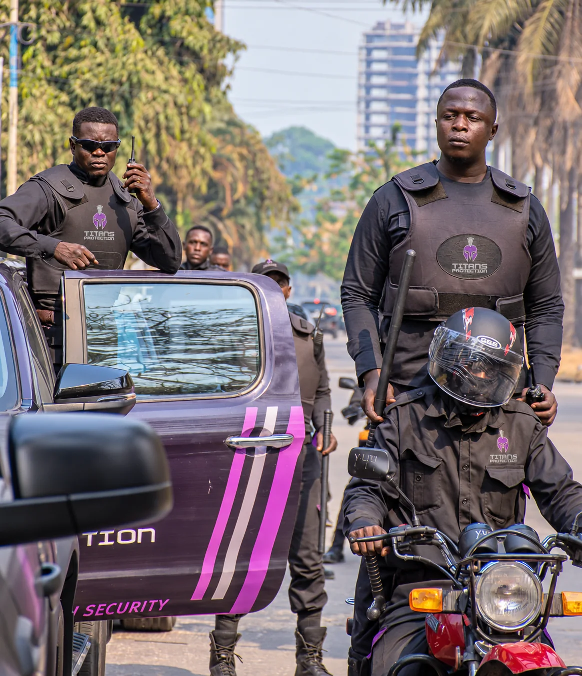 Titans protection officers in branded uniforms beside a company vehicle and motorcycle